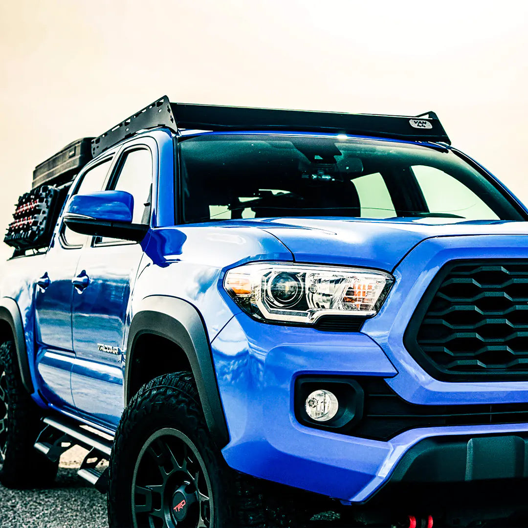 View of the Toyota Tacoma, with a roof rack and a bed rack with a roof top tent