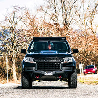 Front view of the Chevy Colorado with a roof rack made in canada by VAN44, tree background and Chevrolet logo