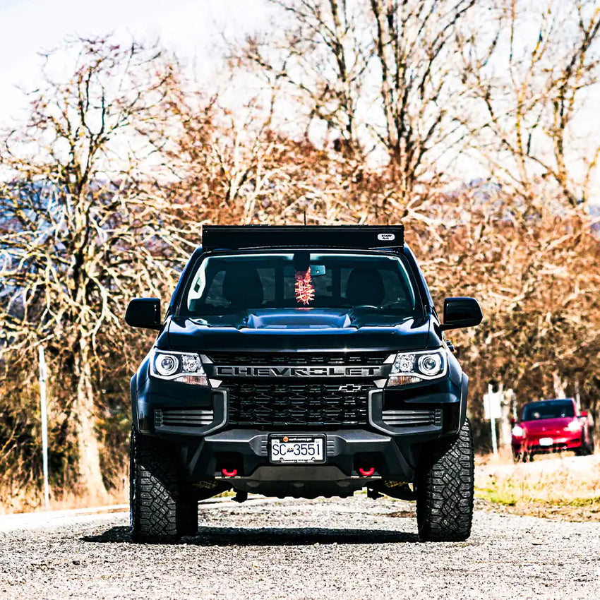 Front view of the Chevy Colorado with a roof rack made in canada by VAN44, tree background and Chevrolet logo