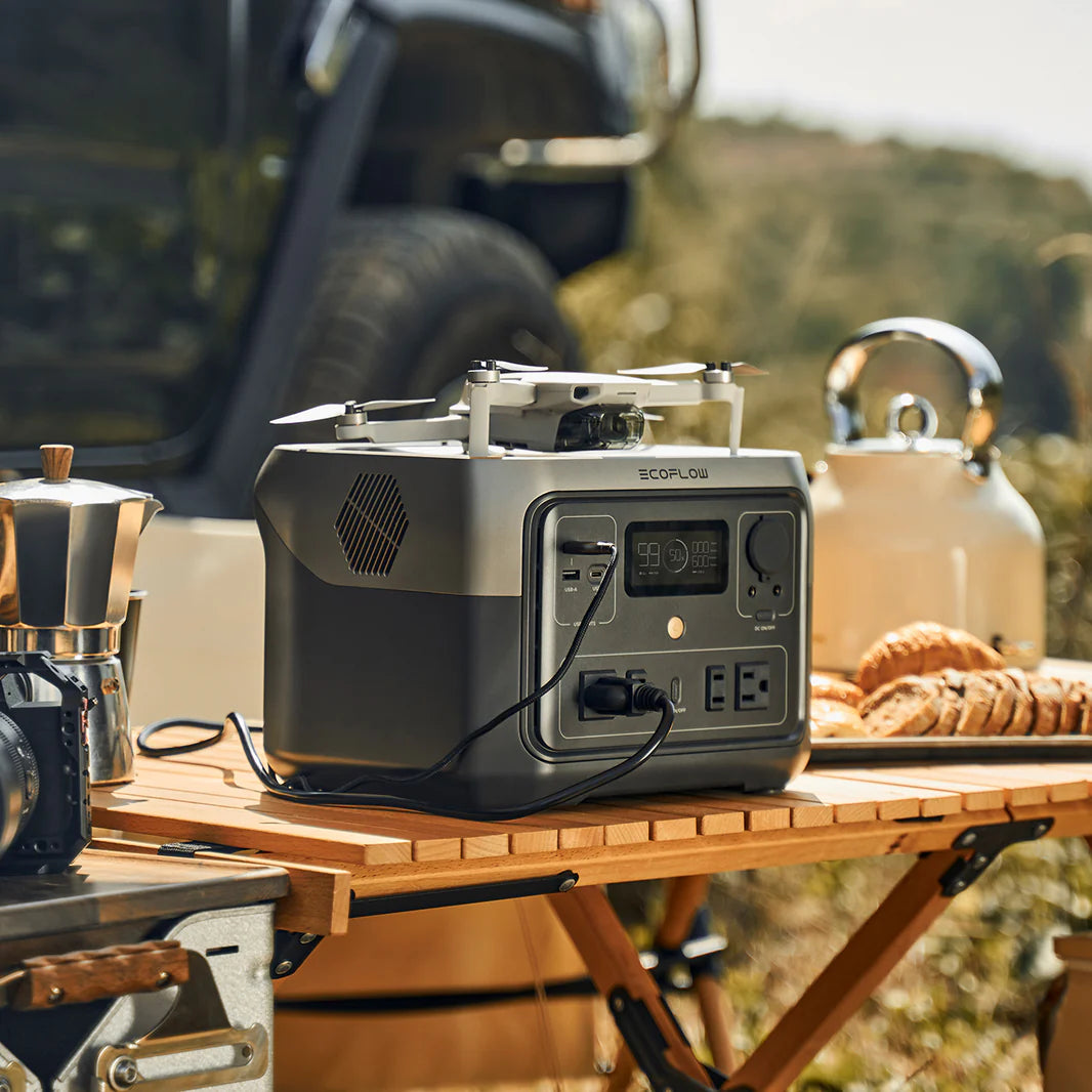 View of the power bank with ac outlet charging a drone in camping