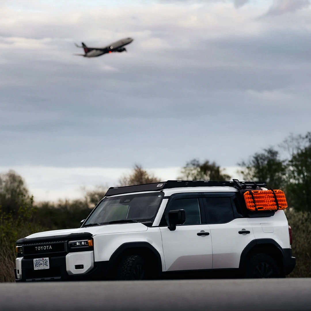 Large view of the Toyota with the tractions boards and a plan in the Sky