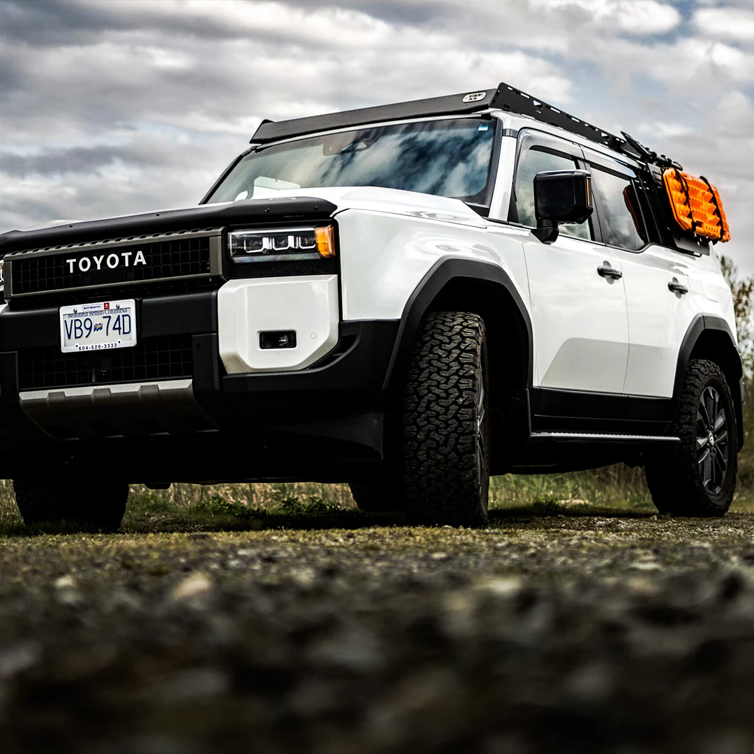 Front view of the Toyota Land Cruiser LC250, a 2024 or 2025 model with an overland roof rack and a traction board