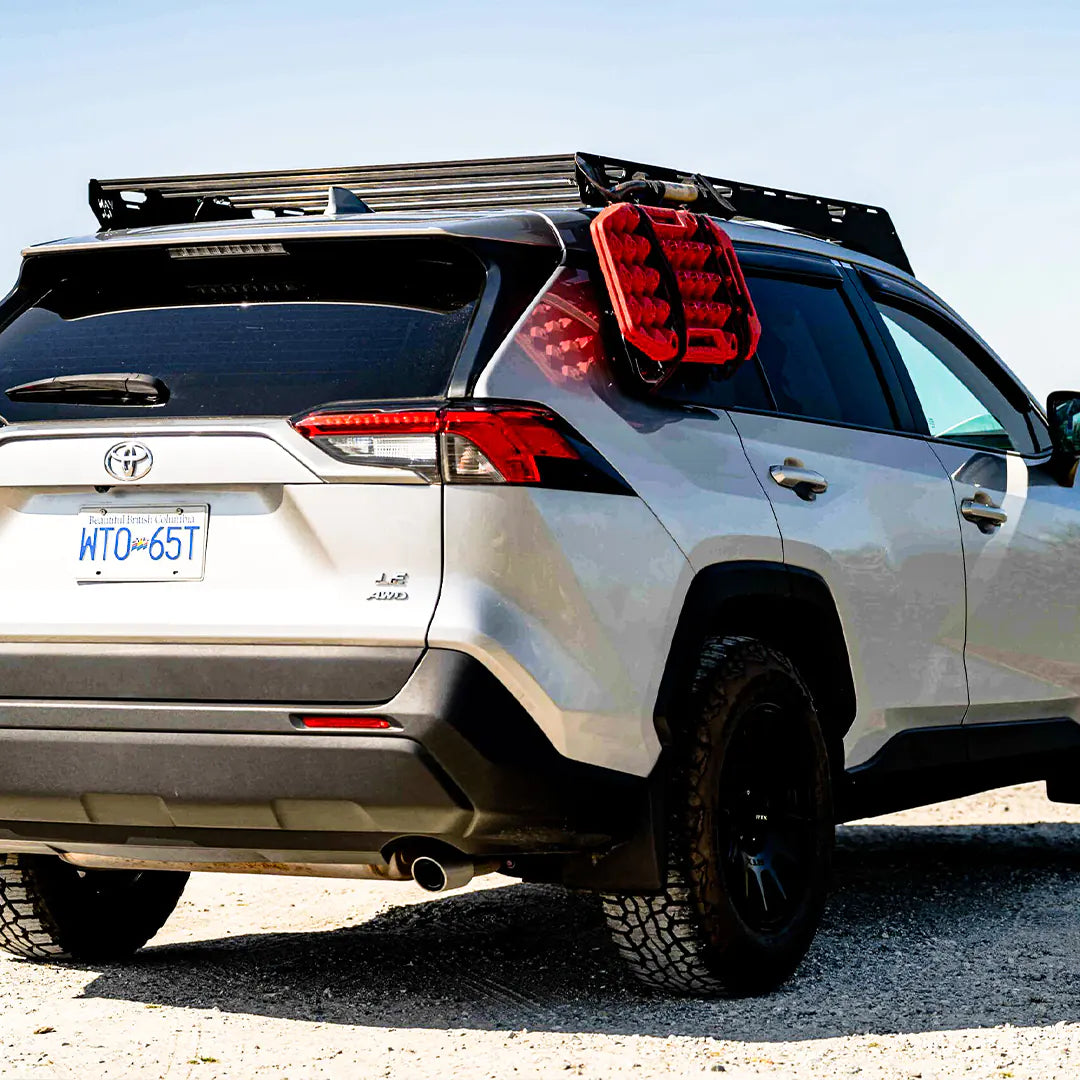 Rear view of the Toyota RAV4 with a roof rack and a traction board